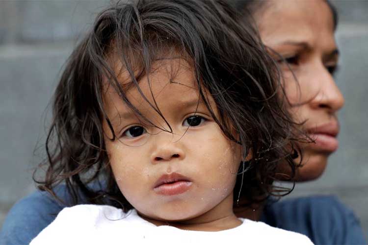 Jesús Funes, de 19 meses, es sostenido por su madre, Diva Funes, ambos inmigrantes de Honduras, tras ser esoltados de regreso a Reynosa, México, el jueves, 21 de junio de 2018. La familia, que buscaba asilo, fue advertida por funcionarios que si cruzaba ilegalmente sería separados por lo que decidieron retornar voluntariamente.