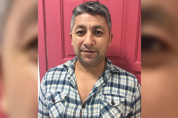 Juan Luis con una camisa azul a cuadros delante de una puerta rosa