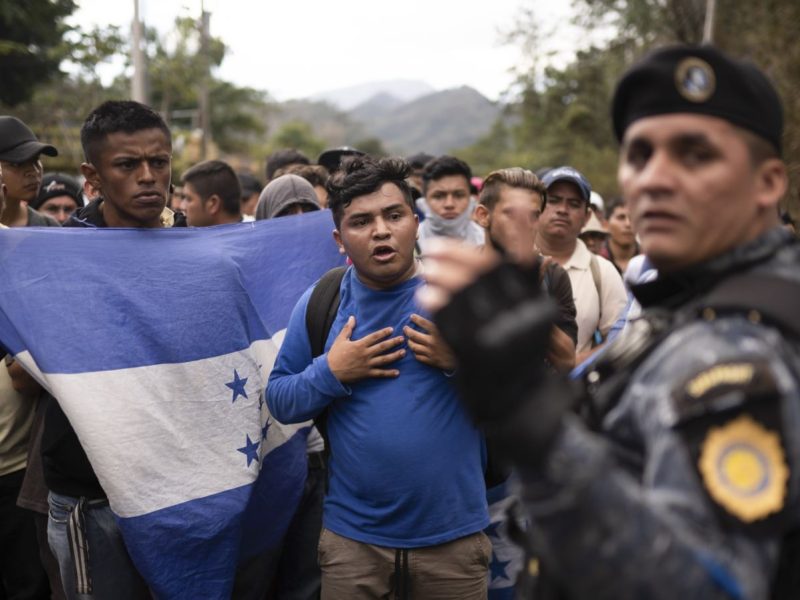 Migrantes hondureños, enarbolando la bandera de su país, se detienen ante policías guatemaltecos cerca de Agua Caliente, Guatemala, el 16 de enero de 2020.