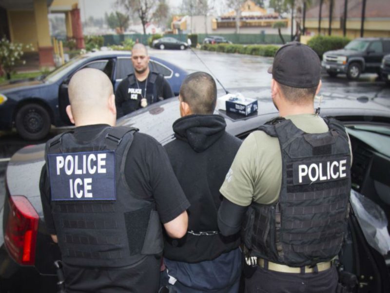 Agentes de ICE deteniendo a migrante