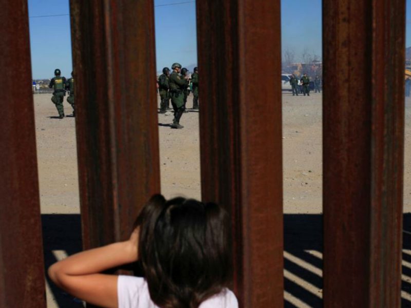 Niña en el muro fronterizo frente a agentes de la CBP Reuters VOA