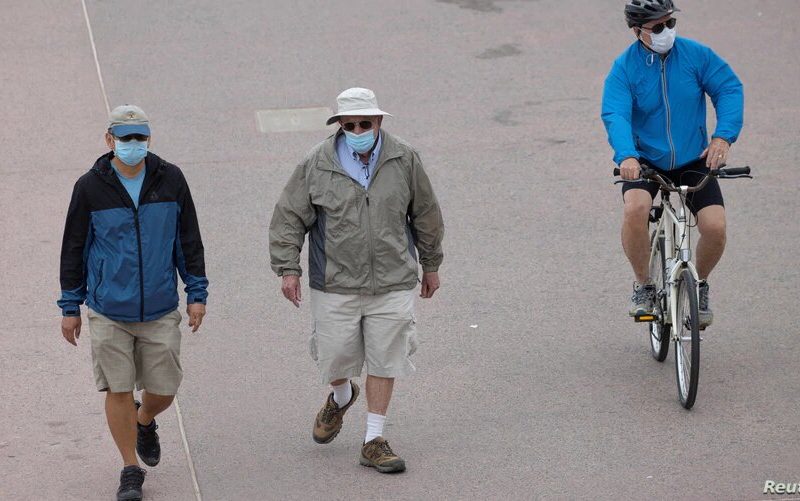 Algunas personas usan cubrebocas en un paseo frente a la playa en Huntington Beach, California, el 1 de julio de 2020. Foto: Voz de América