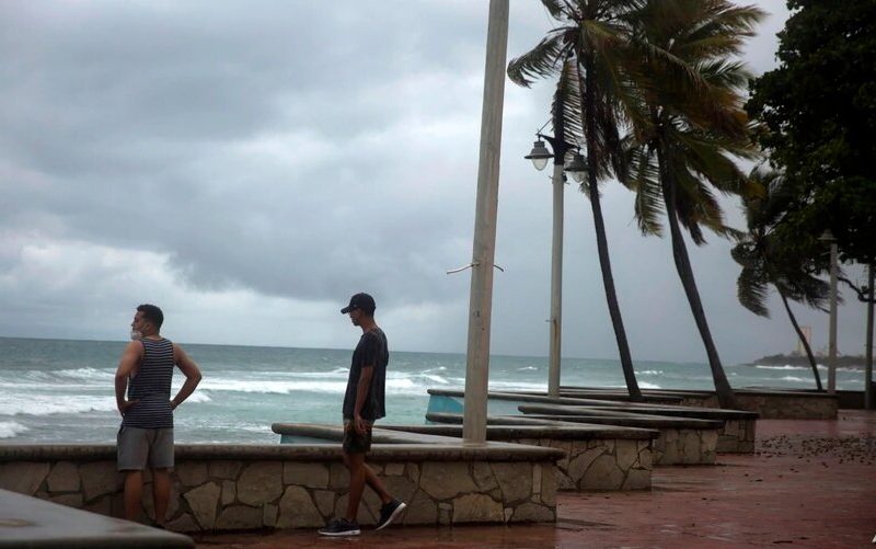 Los hombres miran el mar durante la presencia de la tormenta Isaías en Santo Domingo antes de que se convirtiera en huracán. Foto: VOA, AFP