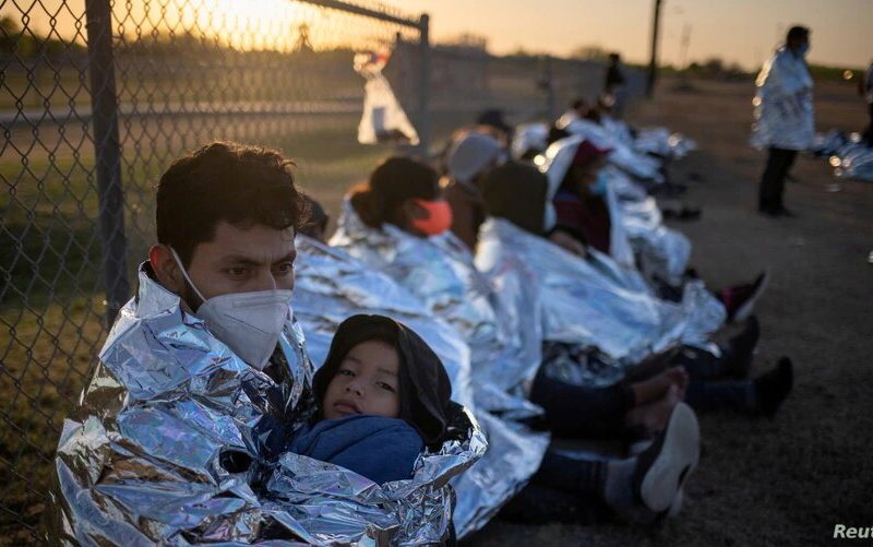Migrantes centroamericanos con niños esperan en un campo de béisbol después de cruzar el Río Grande hacia Estados Unidos en balsas. La Joya, Texas, 19 de marzo de 2021.