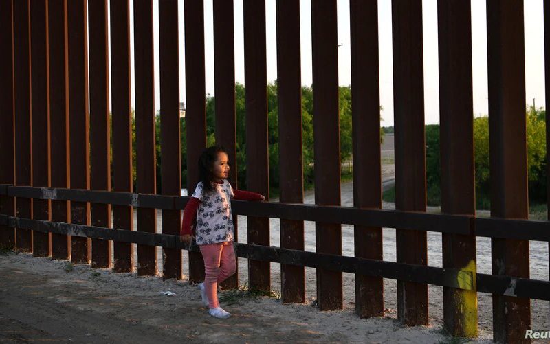 Dos bases militares en Texas resguardarán a niños migrantes no acompañados. Una pequeña, que forma parte de un grupo de migrantes llegados de Centroamérica, camina junto a la valla fronteriza que separa Estados Unidos y México, tras entrar al país de manera irregular, el 6 de abril de 2019.