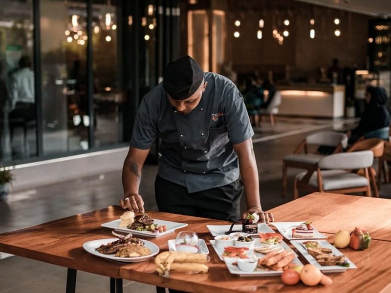 Chef vestido de gris, acomodando platos en un restaurante