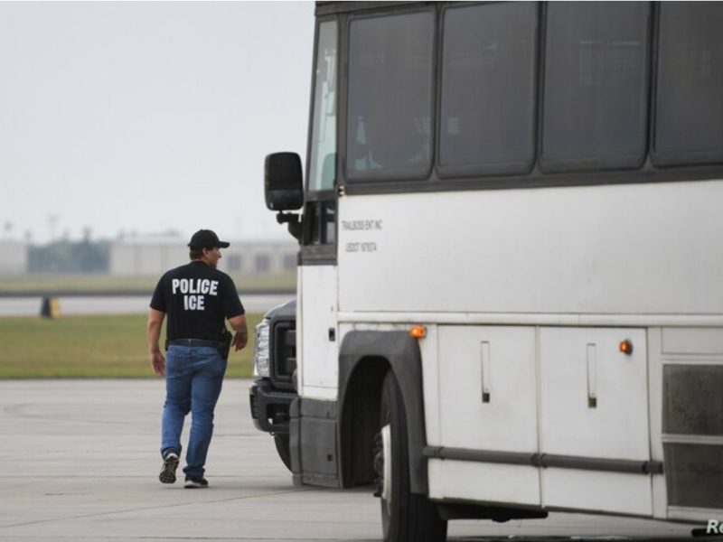 Un oficial de inmigración de EE. UU. camina al lado de un bus para transportar inmigrantes que serán deportados desde el aeropuerto internacional de Brownsville, Texas, en mayo de 2018.
