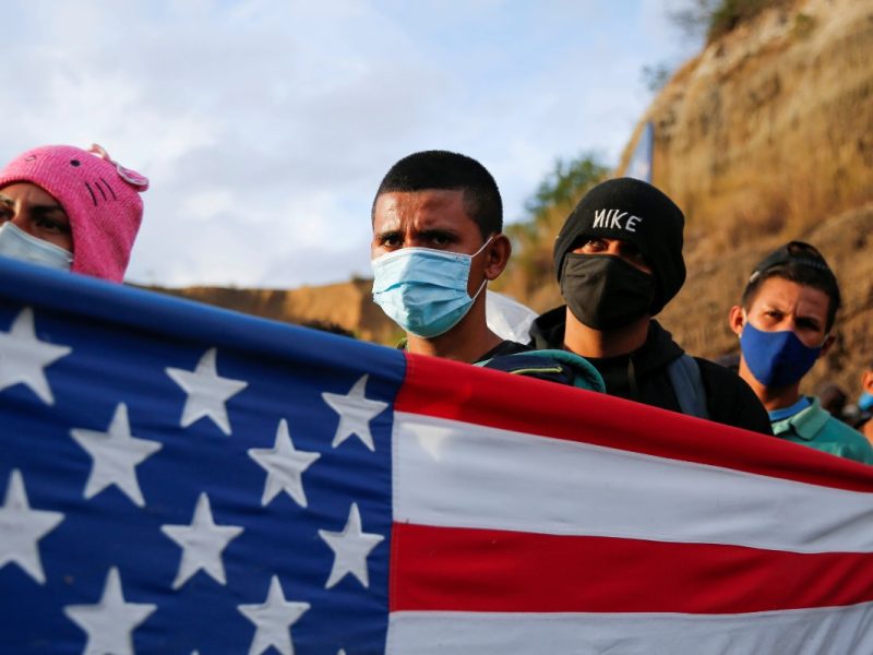 Un grupo de migrantes hondureños muestra una bandera de Estados Unidos