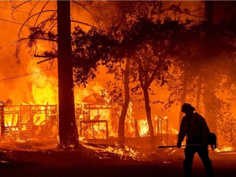 Un bombero pasa junto a una casa en llamas en un incendio en el condado de Plumas, California, el 24 de julio de 2021.