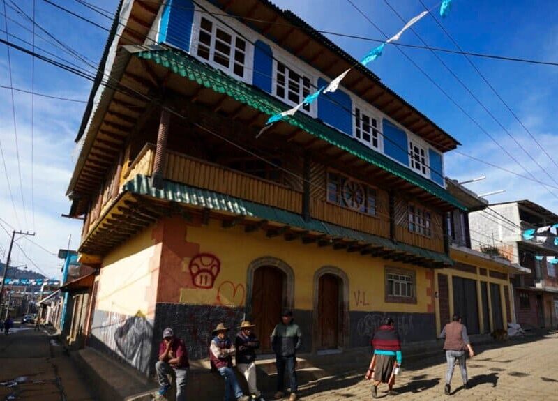 Vecinos reunidos junto a una casa construida con dinero proveniente de remesas, en la comunidad indígena puerpecha de Comachuén, Michoacán, México, en enero de 2022.