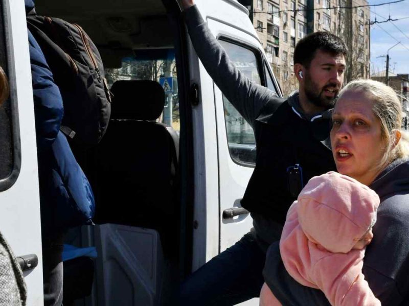 Una mujer con un niño sube a un autobús mientras evacuan a los civiles por la guerra en Ucrania,
