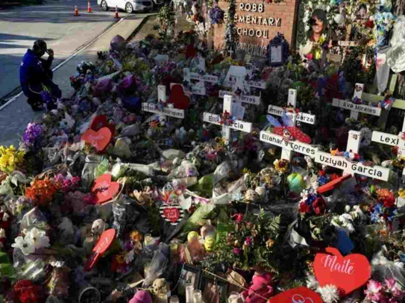 Un hombre se arrodilla el 2 de junio de 2022 frente a un sitio en memoria de las víctimas de un tiroteo en la escuela primaria Robb ocurrido el 24 de mayo, en Uvalde, Texas. Ahora los familiares presentarán una demanda colectiva.