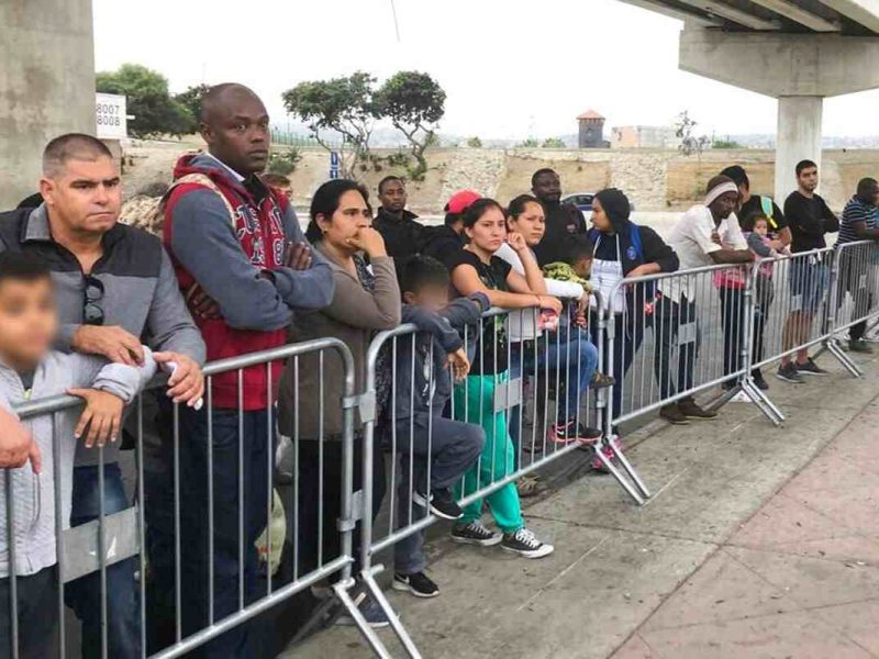 Solicitantes de asilo bajo Quédate en México escuchan si sus nombres son llamados en un cruce fronterizo con EEUU el 26 de septiembre de 2019.