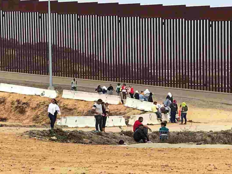 MIgrantes piden asilo en el cruce del muro fronterizo.