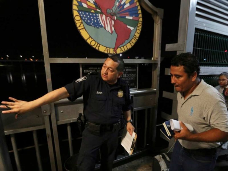 Un agente fronterizo estadounidense le da indicaciones a una familia de migrantes