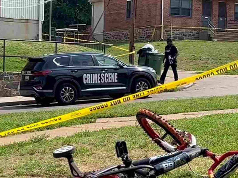Un oficial de policía pasa frente a la bicicleta de un niño después de un tiroteo masivo en la escena de una fiesta del fin de semana festivo del 4 de julio en Baltimore, Maryland.