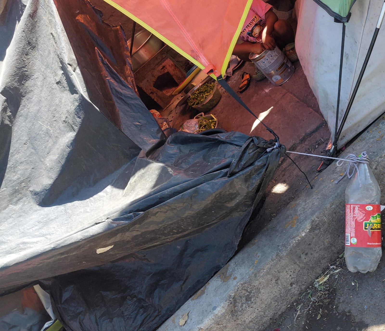 Los migrantes sostienen sus casas provisionales con botellas, para sostenerlas del aire