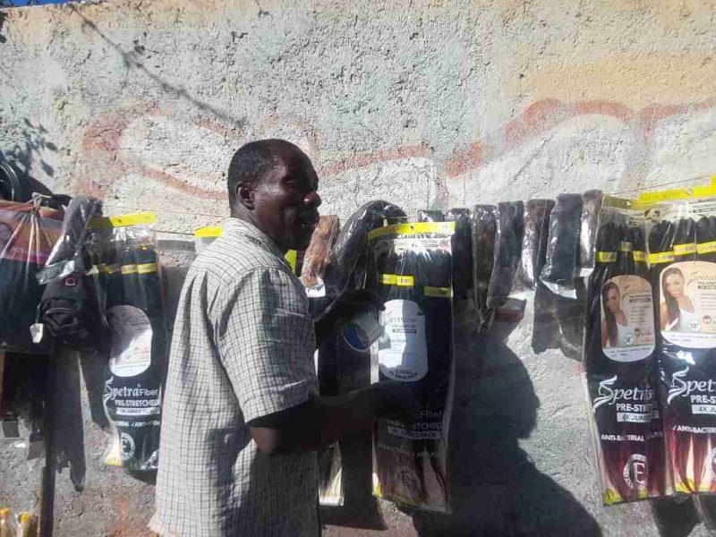 Joven haitiano hace trencitas y vende artículos de belleza en frente del bosque de Tláhuac