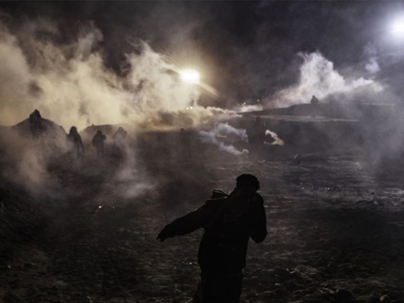 Migrantes corren del gas lacrimógeno lanzado por agentes de Protección Fronteriza de EE.UU. hacia el lado mexicano de la valla en la frontera, después que escalaron la valla tratando de cruzar a San Diego, California desde Tijuana, México, el martes 1 de enero de 2019.