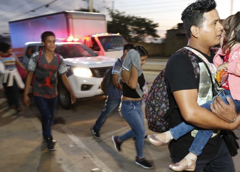 Decenas de migrantes que buscan llegar a Estados Unidos caminan por una carretera mientras salen de San Pedro Sula, Honduras, al amanecer del martes.