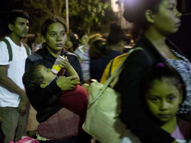 Glasys Menjiva lleva en brazos a su hijo de 16 meses mientras aguarda en la línea para cruzar la frontera en Agua Caliente, Guatemala. Ella forma parte de la caravana de migrantes que inició el viaje rumbo a EE.UU. el martes.