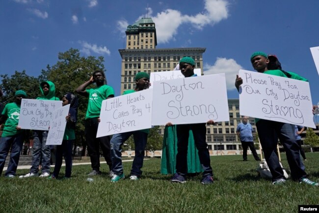 Un grupo de jóvenes sostiene carteles durante una vigilia en honor de las víctimas de un tiroteo masivo en Dayton, Ohio, el domingo 4 de agosto de 2019. REUTERS/Bryan Woolston.