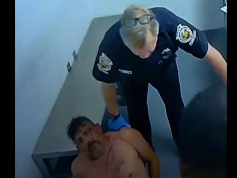 Un policía de Homstead empuja contra la pared a un migrante esposado con ambas manos atrás